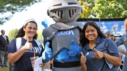 Rivier female students with Raider mascot